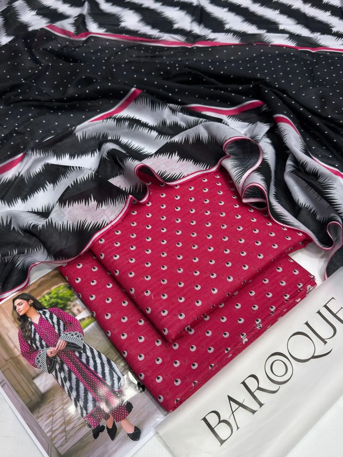 Flatlay of Baroque pink lawn suit with printed dupatta and folded shirt fabric