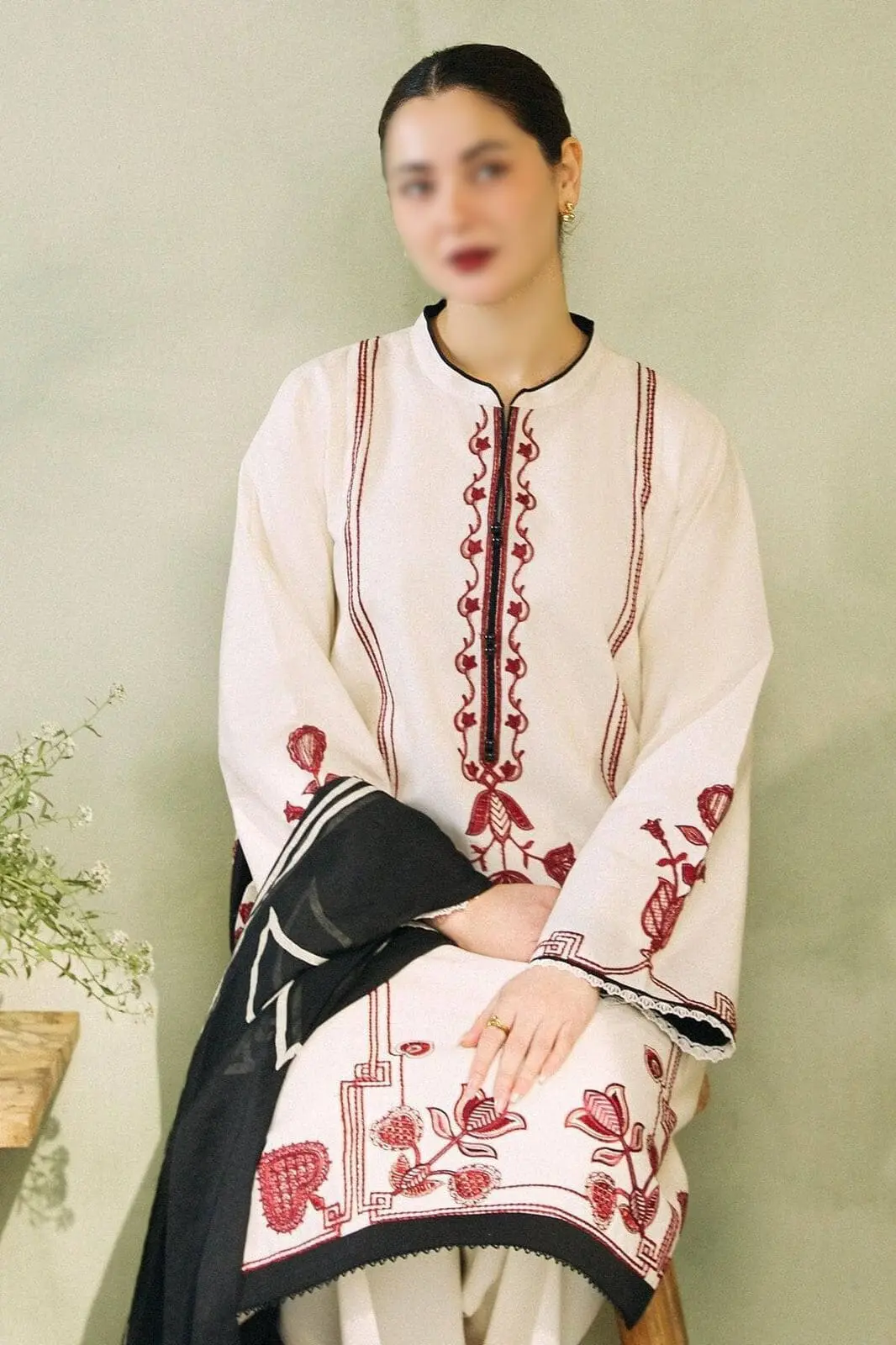 Close-up of model in Zara Shahjahan white embroidered lawn suit with red threadwork and black dupatta.